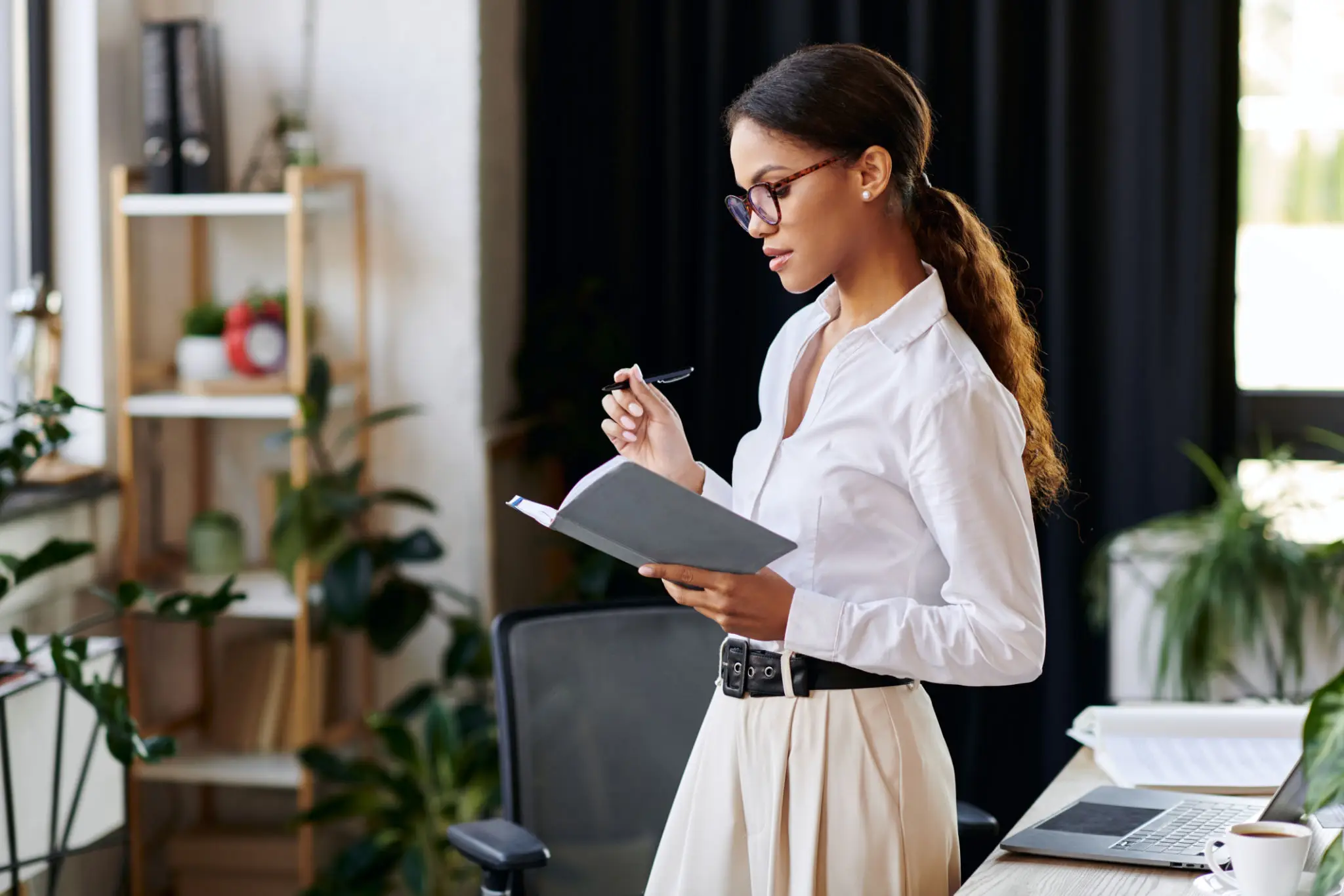 A woman writing notes in a notebook while standing indoors.